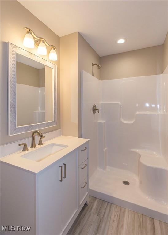 full bathroom with a shower, vanity, and wood finished floors