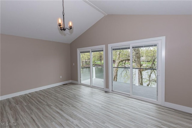 unfurnished room featuring lofted ceiling, baseboards, a water view, light wood-style flooring, and a notable chandelier