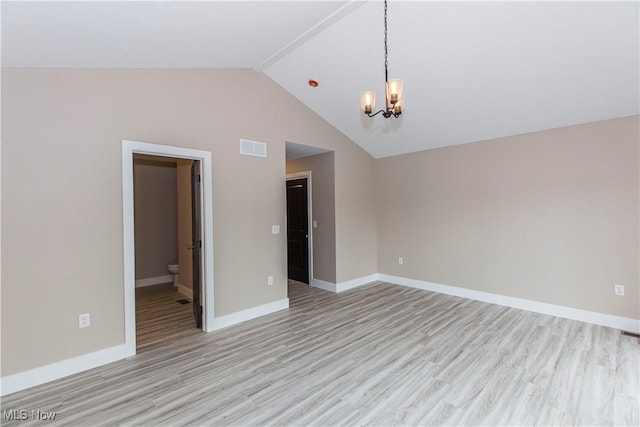 empty room with baseboards, light wood finished floors, lofted ceiling, and a chandelier