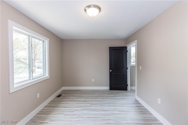 unfurnished room featuring baseboards and light wood-type flooring