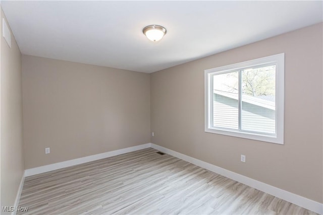 empty room featuring light wood-type flooring and baseboards