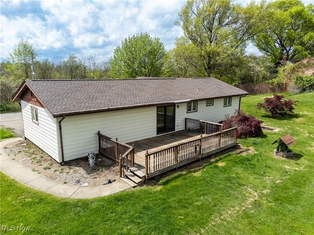 back of property featuring a yard, a deck, and a shingled roof