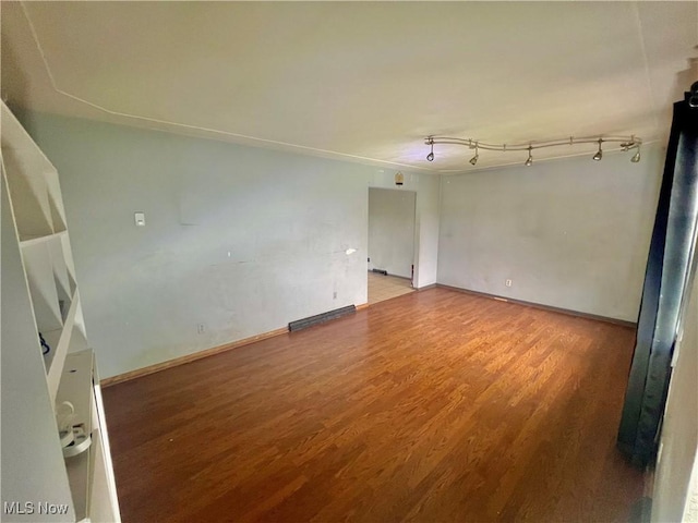 spare room featuring baseboards and wood finished floors