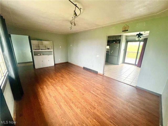 interior space with baseboards, a ceiling fan, and wood finished floors