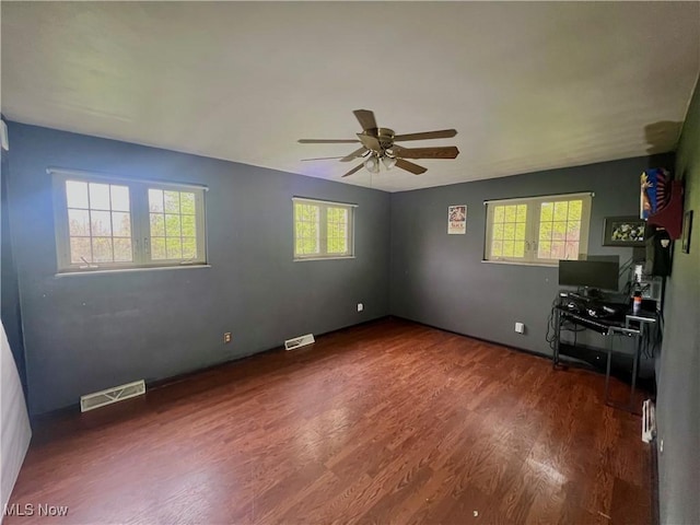 interior space with a ceiling fan, wood finished floors, and visible vents