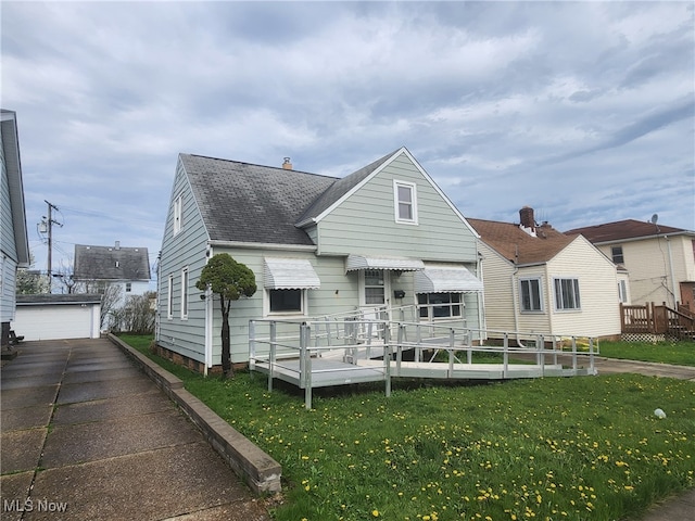 rear view of property featuring an outdoor structure, roof with shingles, and a yard