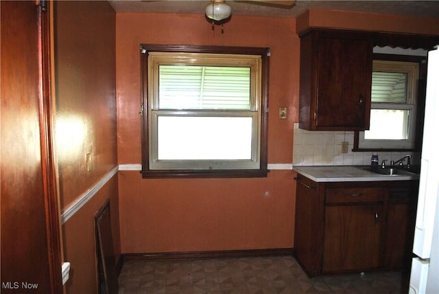 kitchen featuring a sink, dark floors, backsplash, and a wealth of natural light