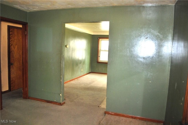 carpeted spare room featuring baseboards
