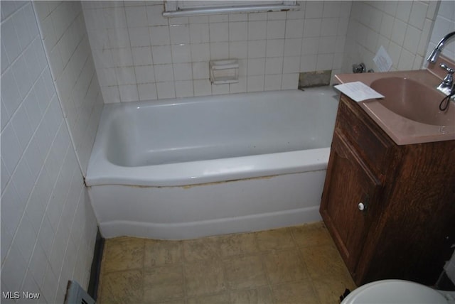 bathroom featuring tile walls, a bathing tub, and vanity