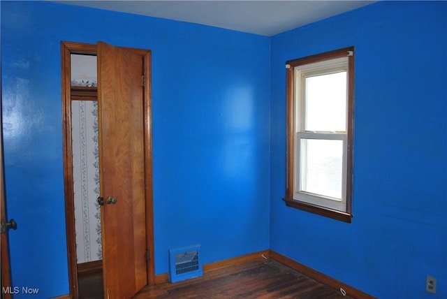 empty room with visible vents, dark wood finished floors, and baseboards