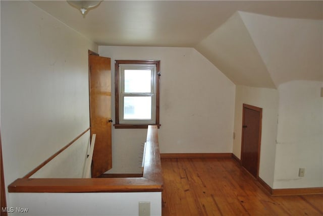 additional living space featuring baseboards, vaulted ceiling, and hardwood / wood-style flooring