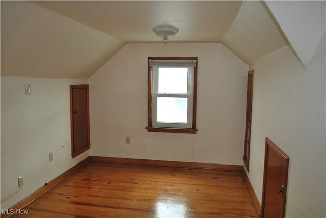 additional living space with baseboards, vaulted ceiling, and light wood finished floors