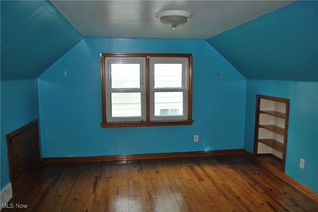 additional living space featuring baseboards, vaulted ceiling, and hardwood / wood-style flooring