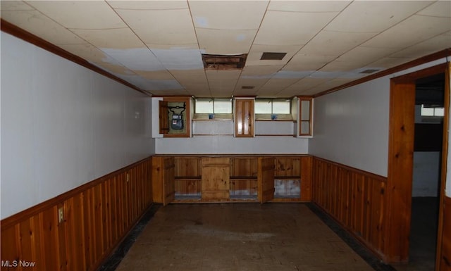 basement with ornamental molding, wainscoting, and wood walls