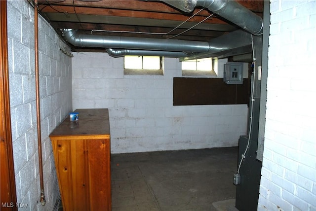 basement featuring concrete block wall and electric panel