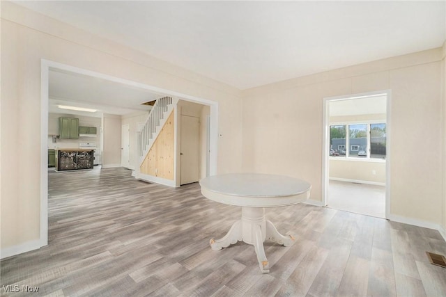 interior space featuring stairway, baseboards, wood finished floors, and visible vents