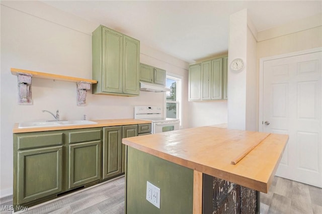 kitchen featuring electric range, a sink, green cabinetry, and under cabinet range hood