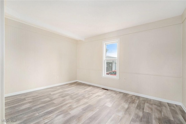 unfurnished room with baseboards, wood finished floors, and visible vents