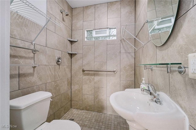 full bathroom featuring tile walls, a tile shower, and a sink