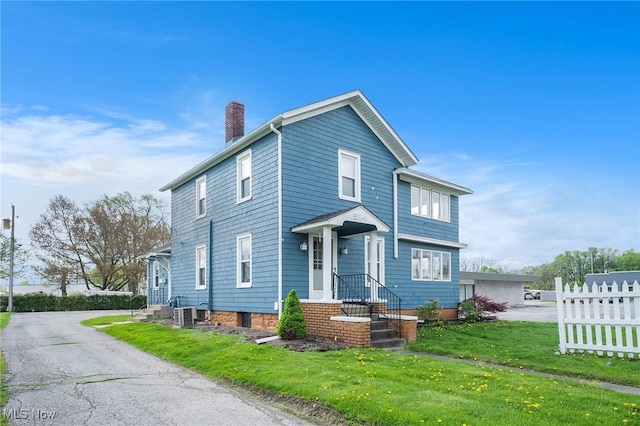 view of front facade featuring fence, a chimney, and a front yard