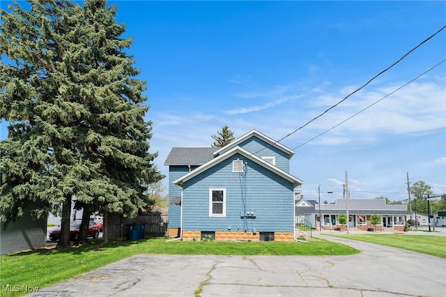 view of side of home featuring fence and a yard