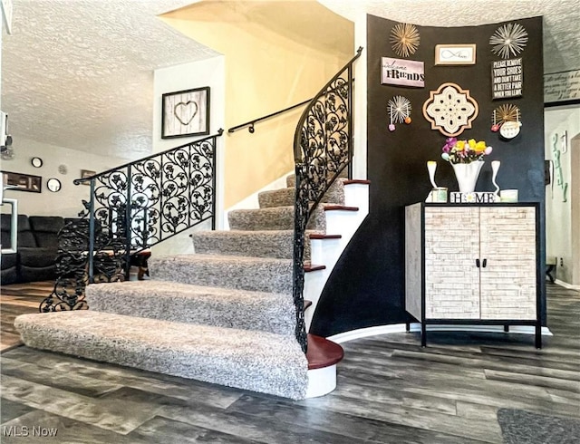 staircase with a textured ceiling and wood finished floors