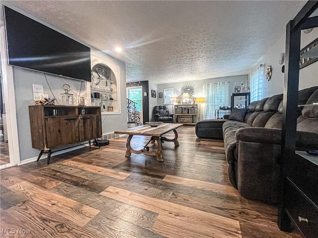 living room featuring a textured ceiling, baseboards, and hardwood / wood-style flooring