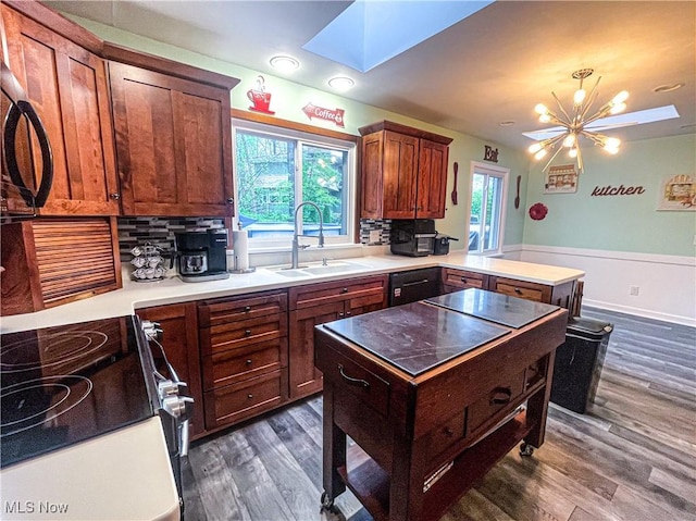 kitchen with a sink, a skylight, dark wood-style flooring, and a peninsula