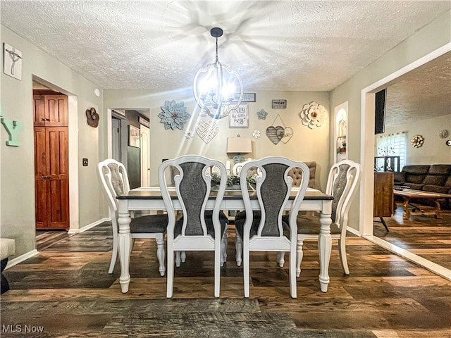 dining area with an inviting chandelier, a textured ceiling, dark wood-style flooring, and baseboards