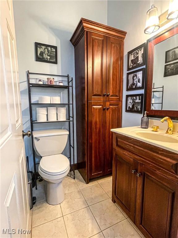 half bathroom with vanity, tile patterned flooring, and toilet