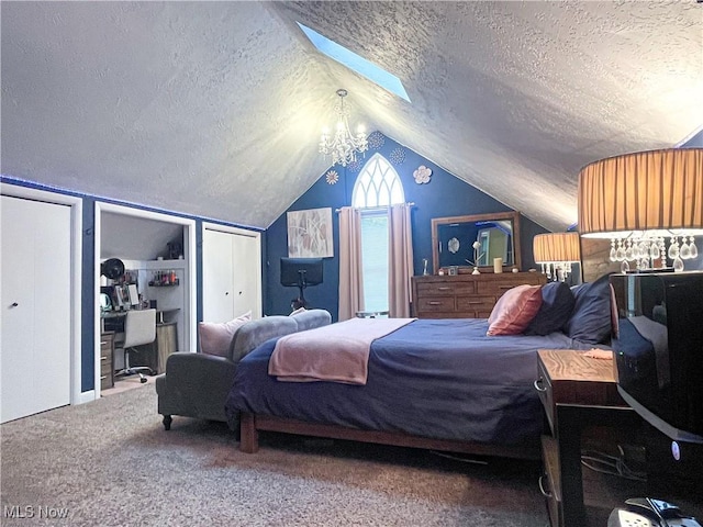 bedroom featuring vaulted ceiling with skylight, carpet floors, two closets, and a textured ceiling