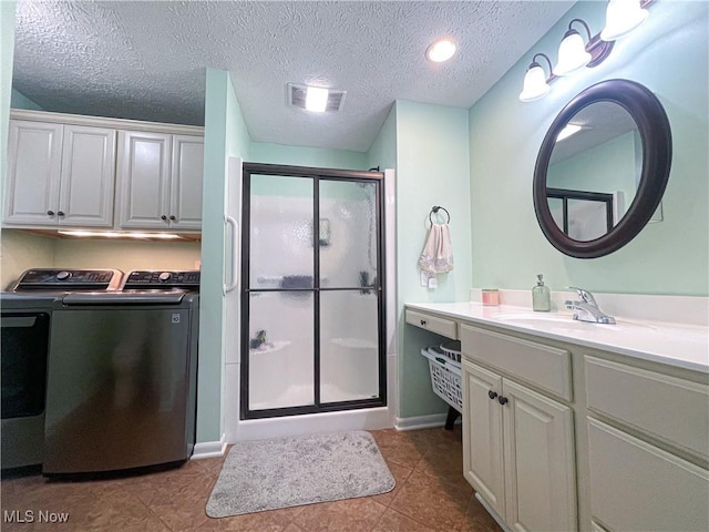 bathroom featuring visible vents, vanity, tile patterned flooring, washer and dryer, and a shower stall