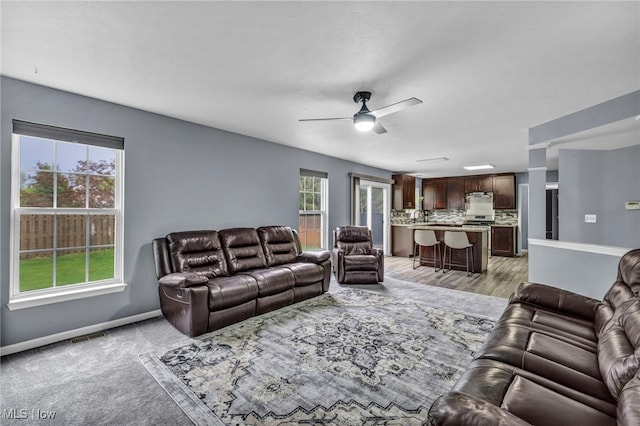 living area with baseboards, ceiling fan, and visible vents