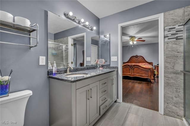 ensuite bathroom with a ceiling fan, a shower stall, vanity, toilet, and connected bathroom