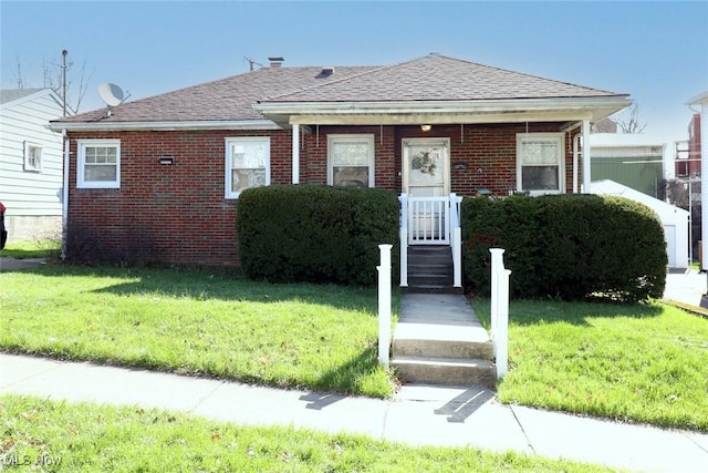 bungalow-style home featuring brick siding, roof with shingles, and a front yard