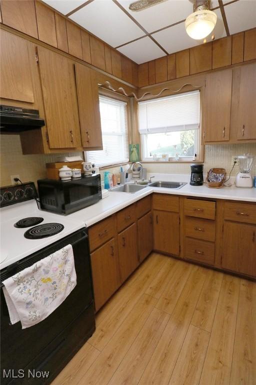 kitchen with black microwave, a sink, light countertops, electric stove, and under cabinet range hood