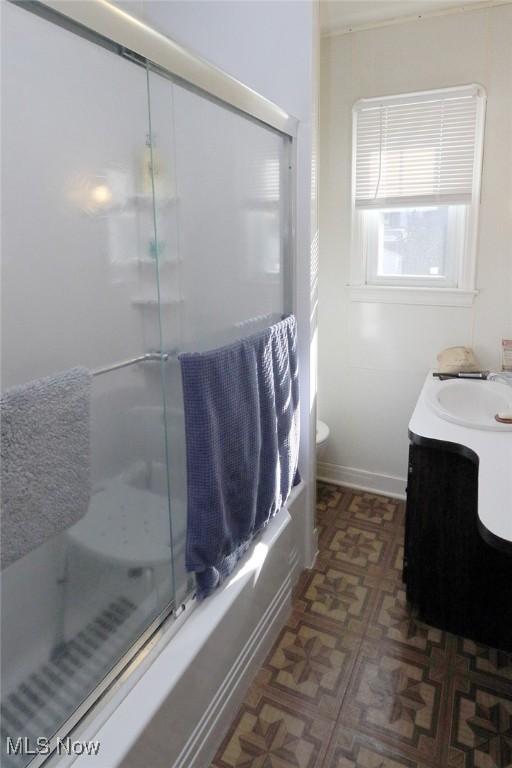 bathroom with combined bath / shower with glass door, tile patterned floors, vanity, and toilet