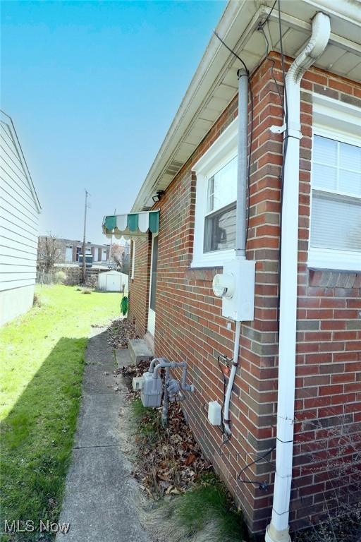 view of side of home with brick siding, a lawn, and entry steps