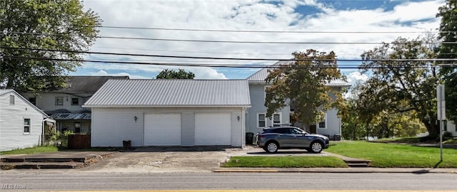 view of front facade with an attached garage, a front lawn, metal roof, and concrete driveway