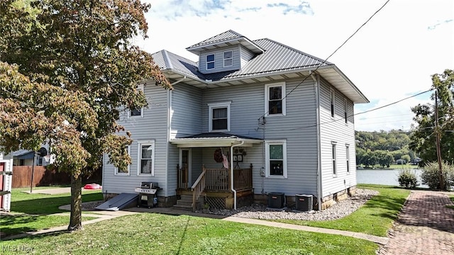 american foursquare style home with central AC unit, fence, a front yard, and metal roof