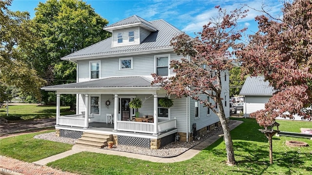 american foursquare style home with covered porch, a front lawn, and metal roof