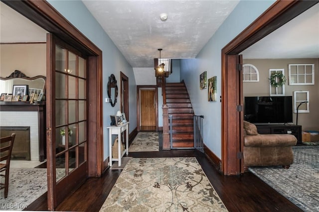 entrance foyer featuring baseboards, dark wood-style flooring, a brick fireplace, and stairs