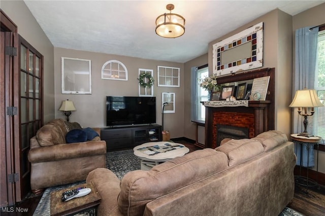 living room with a brick fireplace, baseboards, and wood finished floors