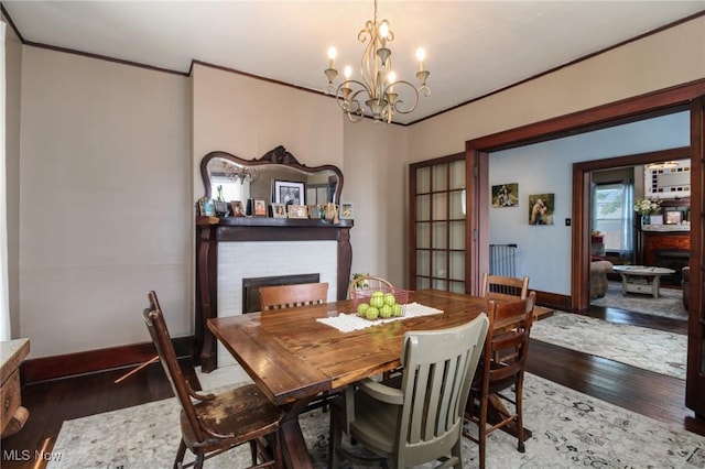 dining space featuring baseboards, a chandelier, ornamental molding, and wood finished floors