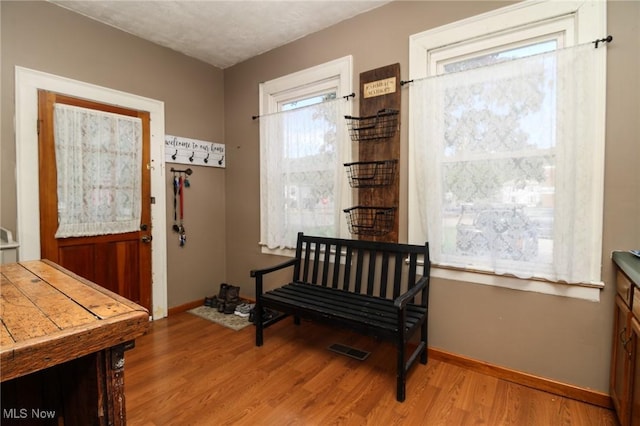 doorway to outside featuring baseboards, wood finished floors, and visible vents