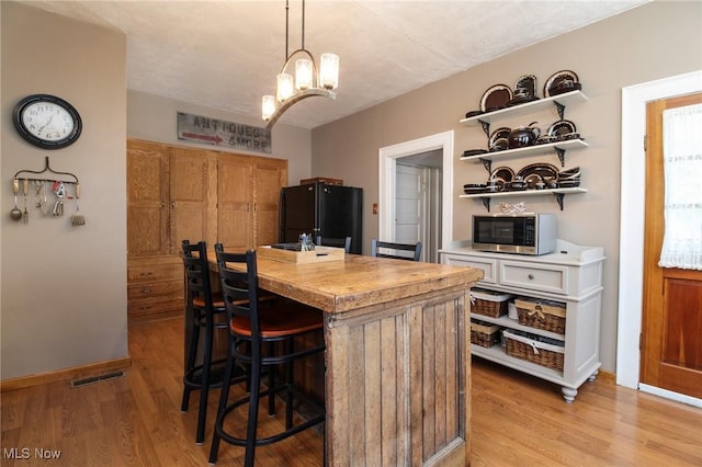 kitchen featuring light countertops, light wood-style floors, stainless steel microwave, and freestanding refrigerator