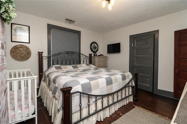 bedroom with baseboards, visible vents, and hardwood / wood-style floors