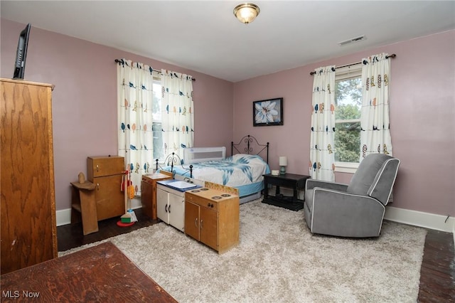 bedroom featuring baseboards, wood finished floors, and visible vents