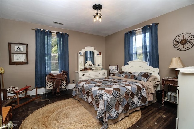 bedroom with baseboards, wood finished floors, and visible vents