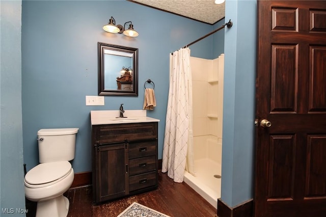 full bath featuring a stall shower, wood finished floors, vanity, baseboards, and toilet